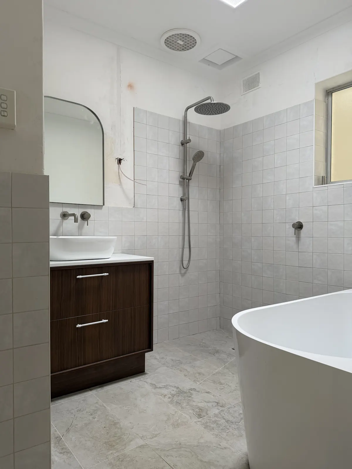 Bathroom with rain shower, freestanding bath and arched mirror