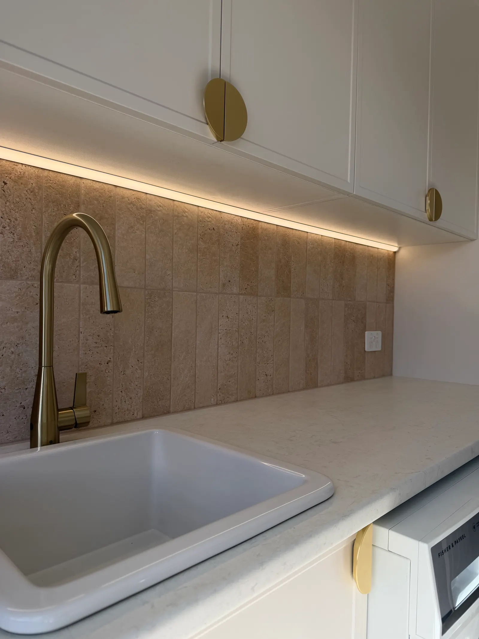 White kitchen sink with a brass mixer tap