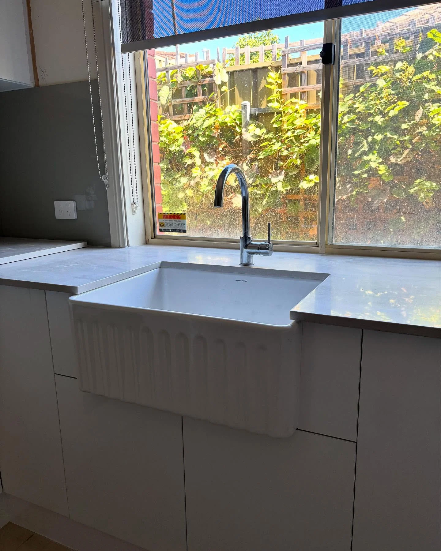 White apron-front kitchen sink and chrome mixer installed by R&J