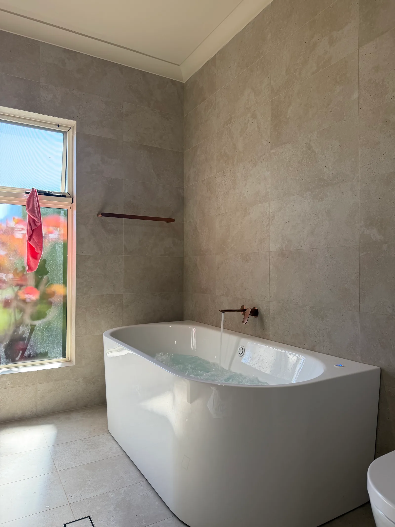 White spa bath with wall-mounted copper fittings